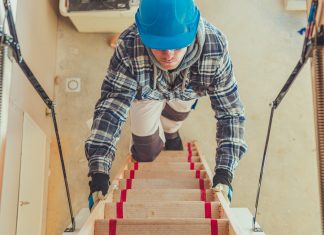 The Top Hazards Of Lone Working And How To Protect Your Workers Construction Worker Walking Upstairs To Take a Look at House Attic. Wooden Second Level Stairs.