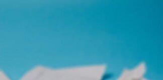 Selective focus of stack of white paper wrinkled receipts in daylight on blue background