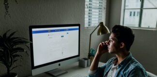 man in blue denim jacket facing turned on monitor
