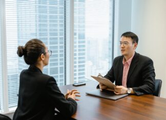 6 Tips to Get Yourself More Competitive In The Job Market Man in Glasses Holding a Folder While Talking to a Woman in Suit