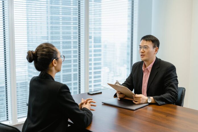 man-in-glasses-holding-a-folder-while-talking-to-a Man in Glasses Holding a Folder While Talking to a Woman in Suit