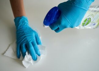 House cleaning software person in blue gloves holding white textile