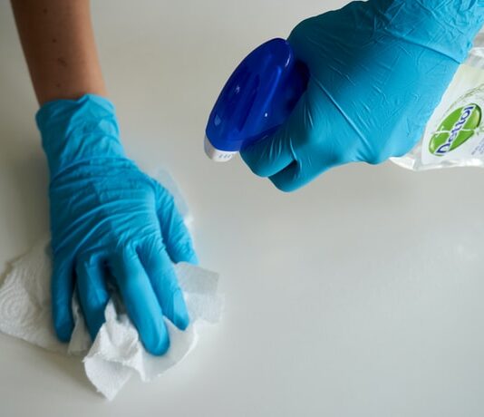 House cleaning software person in blue gloves holding white textile
