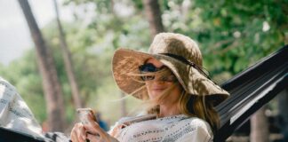 woman lying on black hammock while holding phone