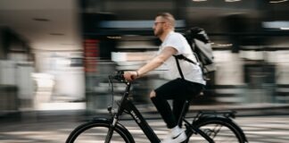 man in white dress shirt and black pants riding on bicycle