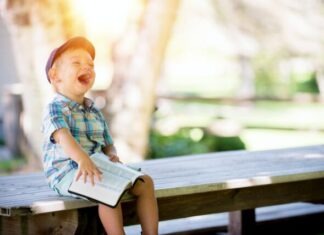 boy sitting on bench while holding a book