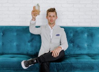 Is a High Education Equal a Rich Future? man in gray blazer raising drinking glass while sitting on sofa