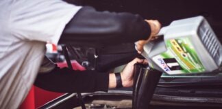 man refilling motor oil on car engine bay
