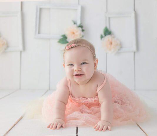 girl crawling on white floor while smiling
