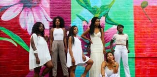 six women wearing white pants posing