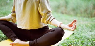 woman in brown long sleeve shirt and black pants sitting on white textile