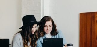 two woman sitting near table using Samsung laptop