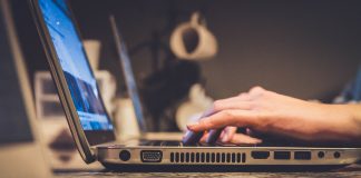 person using silver laptop computer on desk