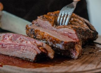 Spotting the Differences between Skirt Steak and Flank Steak person slicing a meat on brown wooden board