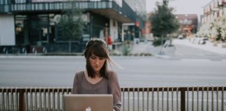 woman in gray shirt sitting on bench in front of MacBook