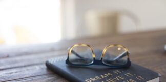 black and brown eyeglasses on book on brown wooden table