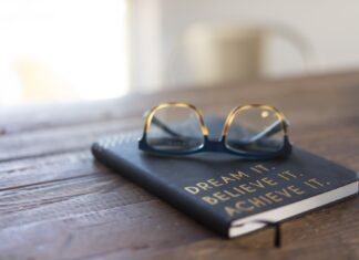 How to achieve your dreams using bitcoin black and brown eyeglasses on book on brown wooden table