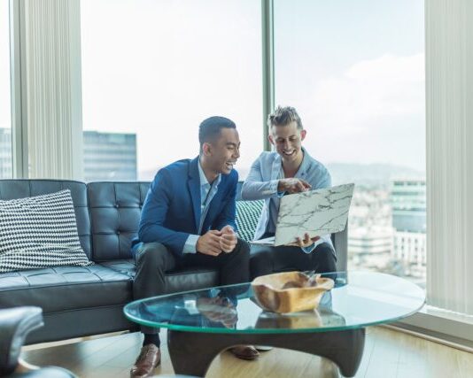 two men in suit sitting on sofa