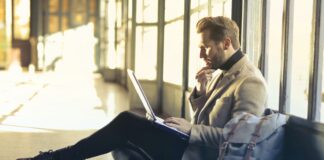 man sitting on floor while using laptop