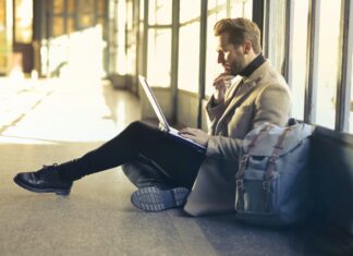 Is Fashion Business a Good Degree? man sitting on floor while using laptop