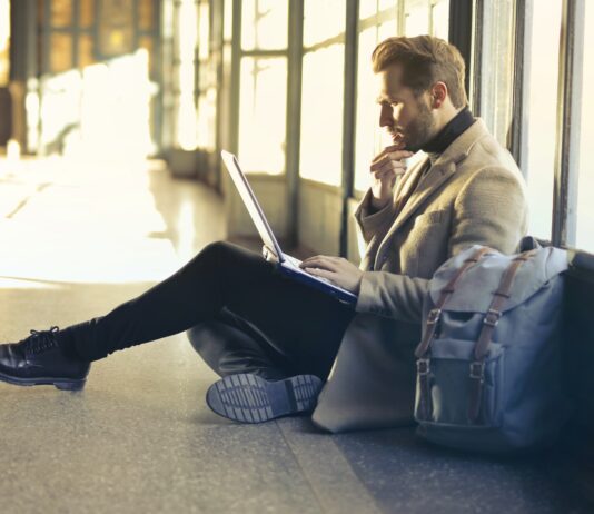 man sitting on floor while using laptop