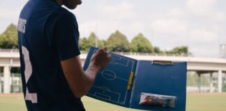 man in blue crew neck t-shirt standing on track field during daytime