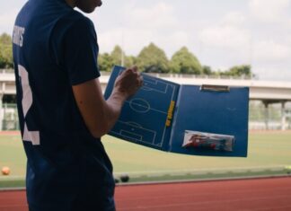 man in blue crew neck t-shirt standing on track field during daytime