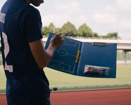 man in blue crew neck t-shirt standing on track field during daytime