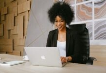 VPS Prestashop Woman in Black Blazer Sitting by the Table While Using Macbook