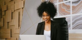 Woman in Black Blazer Sitting by the Table While Using Macbook