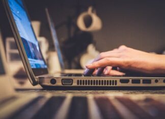 person using silver laptop computer on desk