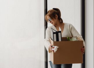 National Debt Relief: Protecting Yourself from Scams and Finding Reliable Solutions a woman crying while carrying her items in a box after being a victim of a debt relief scam.