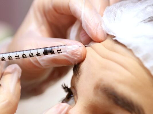 a woman getting her eyebrows examined by a doctor