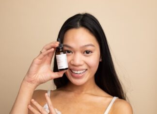 4 Treatments for Hyperpigmentation on Your Face woman in white tank top holding white labeled bottle