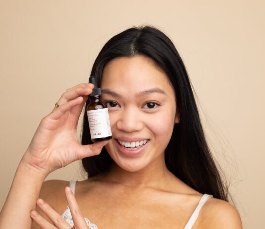 woman in white tank top holding white labeled bottle
