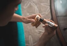 person putting e-juice on gold Wismec variable vaporizer