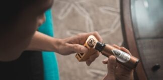 person putting e-juice on gold Wismec variable vaporizer