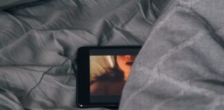 black Android smartphone on gray bed sheet