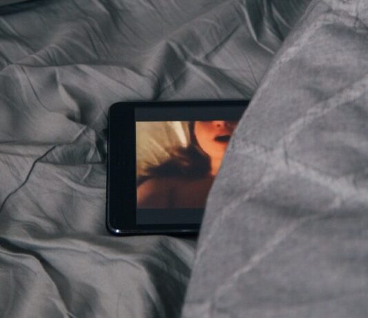 black Android smartphone on gray bed sheet