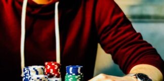 person holding playing cards beside poker chips