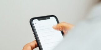 man in white top holding iPhone