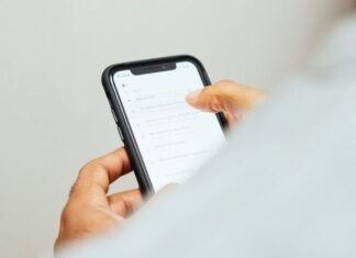 Role of Artificial Intelligence in Enhancing Online Betting Experiences man in white top holding iPhone