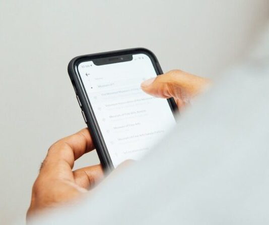 man in white top holding iPhone