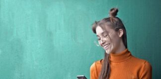 Woman in Orange Turtleneck Sweater Holding Black Smartphone
