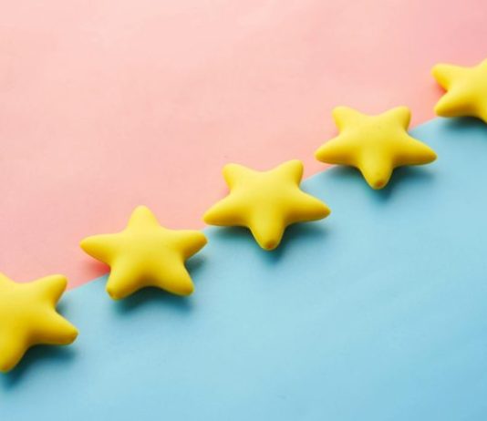 Attica’s Showdown with Fake Reviews Yellow stars on pink and blue pastel background for rating or review concept.