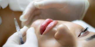 Close-up of a woman receiving a lip augmentation with a syringe by a professional.