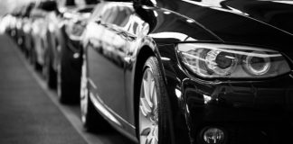Close-up black and white image of a luxury car line-up focusing on vehicle headlights.