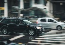 Maximizing Your Compensation After a Car Crash Vehicles speeding through a city street with a visible zebra crossing and blurred motion effect.