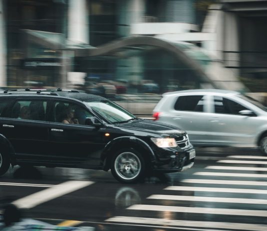 Maximizing Your Compensation After a Car Crash Vehicles speeding through a city street with a visible zebra crossing and blurred motion effect.