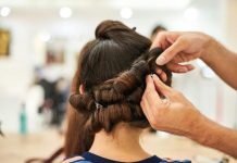 How to Get Celebrity Hair—Straight from Kenna Kennor (A.K.A. Britt Lower’s Husband & Celebrity Hair Guru) Close-up of a stylist crafting an intricate updo hairstyle in a modern salon.